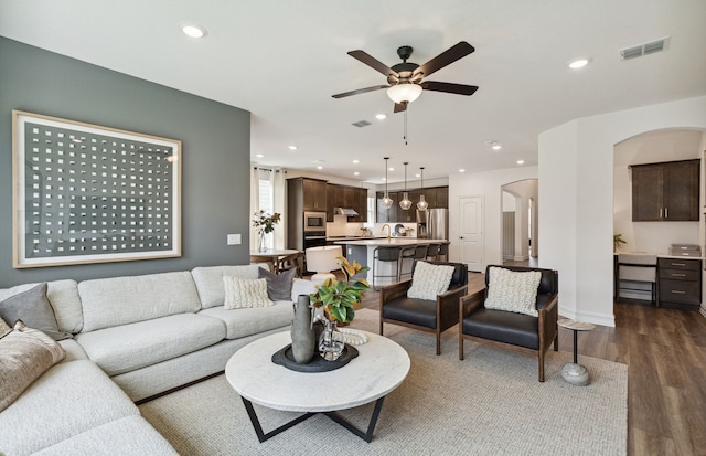 living room featuring ceiling fan, sink, and dark wood-type flooring