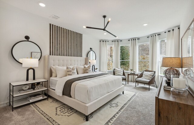 bedroom with light colored carpet and ceiling fan with notable chandelier