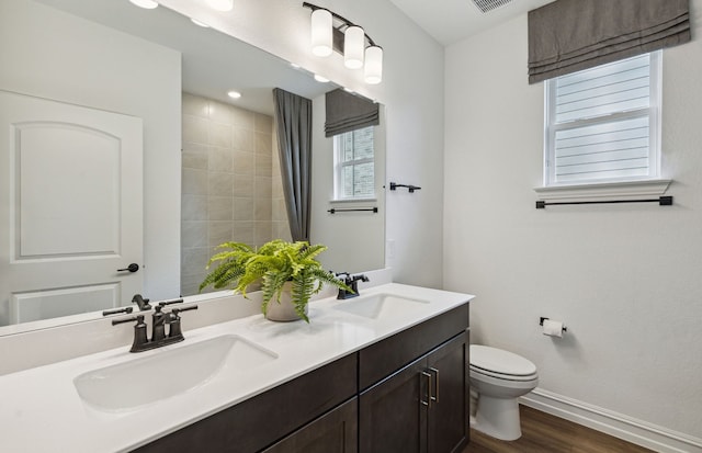 bathroom featuring wood-type flooring, vanity, toilet, and walk in shower