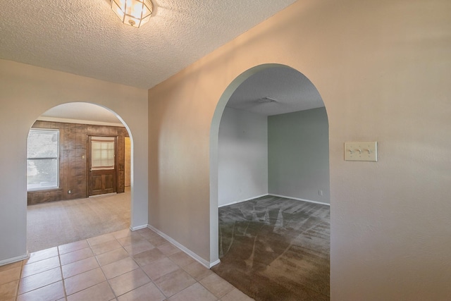 corridor with light colored carpet and a textured ceiling