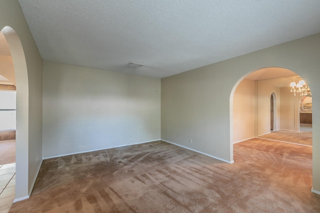 spare room featuring light carpet and a textured ceiling