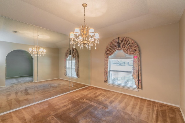 unfurnished dining area featuring carpet flooring, a chandelier, and a tray ceiling