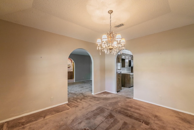 unfurnished dining area featuring a raised ceiling, a textured ceiling, light carpet, and a notable chandelier