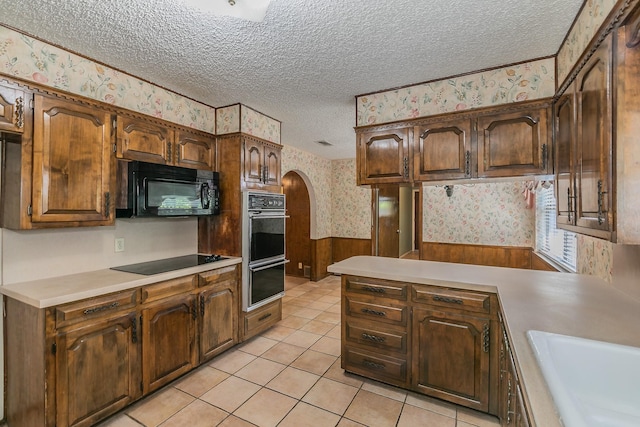 kitchen featuring sink, light tile patterned floors, a textured ceiling, and black appliances