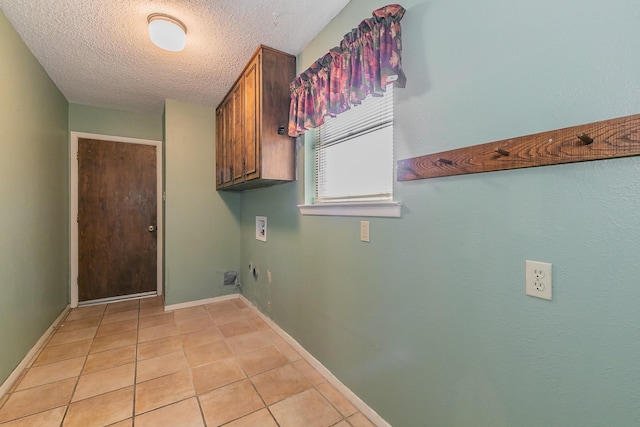 laundry area with hookup for a washing machine, light tile patterned floors, a textured ceiling, and cabinets