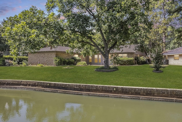 rear view of property with a lawn and a water view