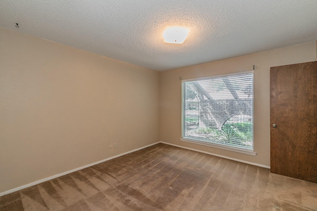 carpeted empty room featuring a textured ceiling