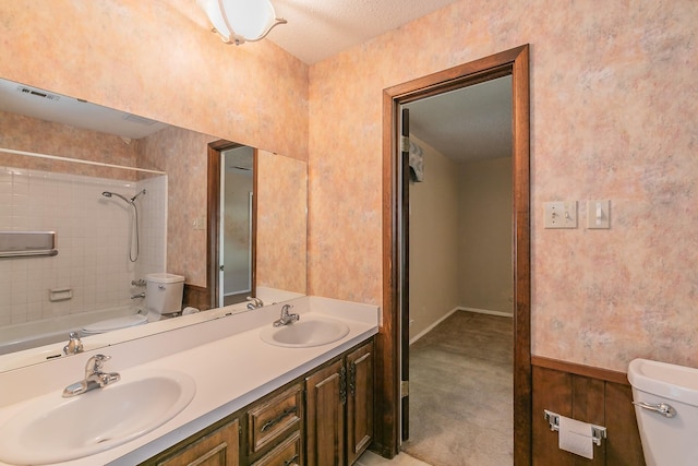 full bathroom featuring vanity, tiled shower / bath, and toilet