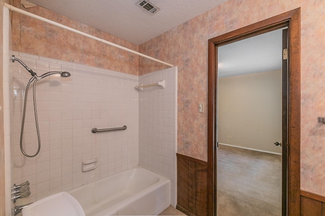 bathroom with tiled shower / bath and a textured ceiling