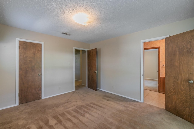 unfurnished bedroom with light colored carpet and a textured ceiling