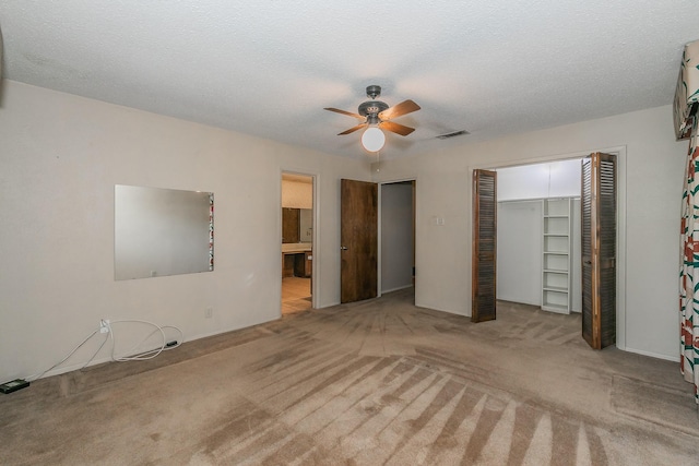 unfurnished bedroom with ceiling fan, light colored carpet, a closet, and a textured ceiling