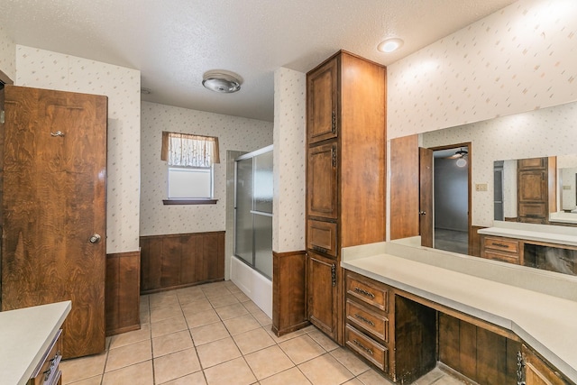 bathroom featuring enclosed tub / shower combo, vanity, tile patterned flooring, and a textured ceiling