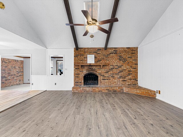 unfurnished living room featuring lofted ceiling with beams, light hardwood / wood-style floors, and a textured ceiling