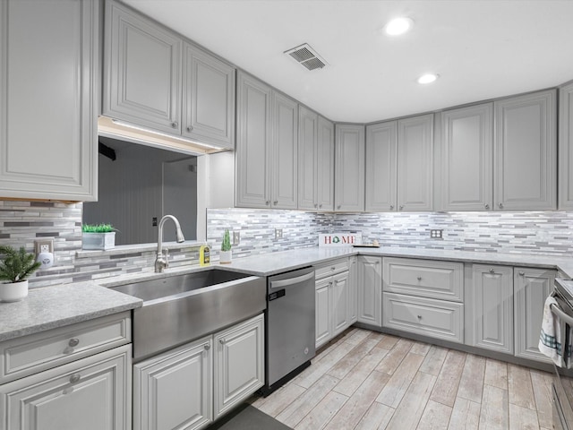 kitchen featuring dishwasher, gray cabinets, light stone countertops, and sink