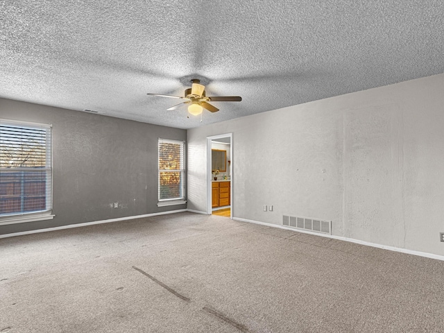 carpeted spare room with ceiling fan and a textured ceiling