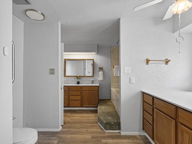 bathroom with hardwood / wood-style floors, vanity, ceiling fan, and toilet