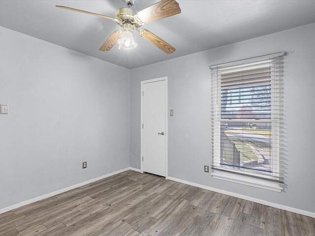 unfurnished room with wood walls, ceiling fan, and light hardwood / wood-style floors