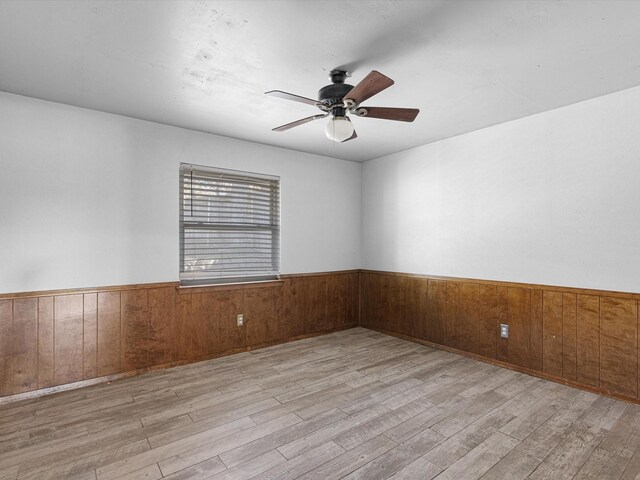 unfurnished bedroom featuring ceiling fan, a closet, wood walls, and light hardwood / wood-style flooring