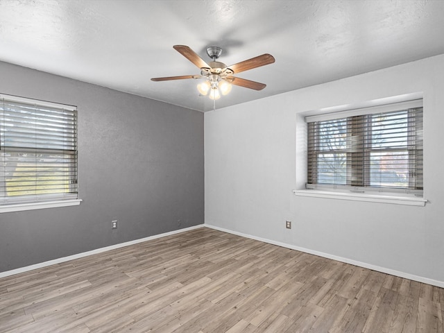 empty room with plenty of natural light, ceiling fan, and light hardwood / wood-style flooring