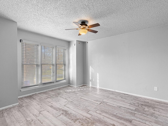 spare room with ceiling fan, light wood-type flooring, and a textured ceiling