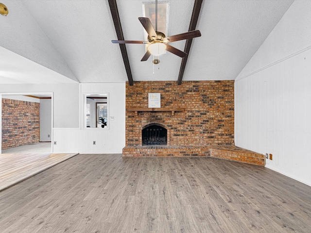 unfurnished living room featuring hardwood / wood-style flooring, ceiling fan, a textured ceiling, and brick wall