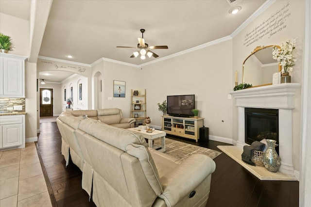 tiled living room featuring ceiling fan and crown molding