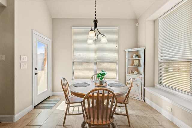 tiled dining space featuring lofted ceiling and a chandelier