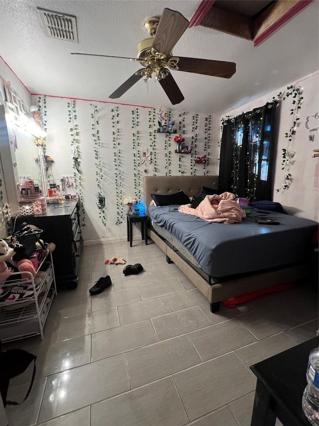 bedroom featuring tile patterned floors, ceiling fan, and a textured ceiling