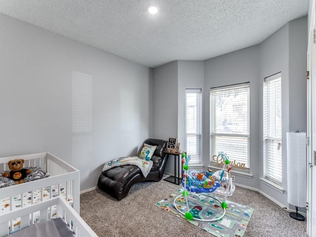 carpeted bedroom with a crib, a textured ceiling, and multiple windows