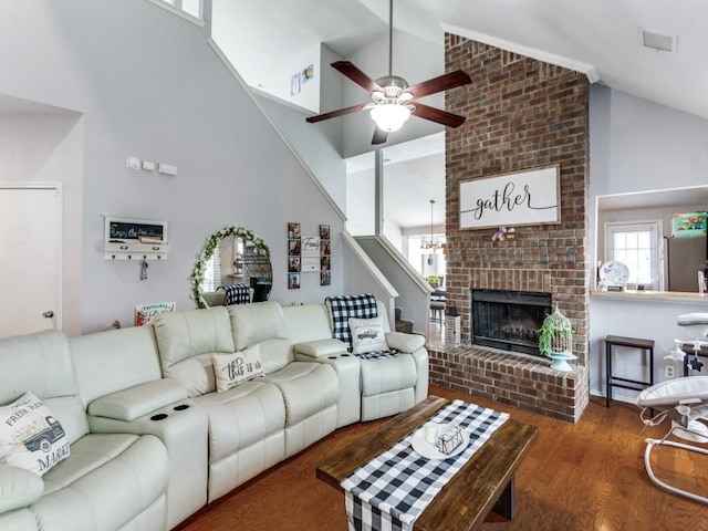 living room with high vaulted ceiling, a brick fireplace, ceiling fan, and dark wood-type flooring