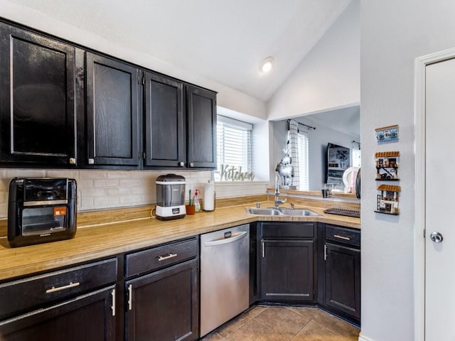 kitchen with decorative backsplash, vaulted ceiling, sink, light tile patterned floors, and dishwasher