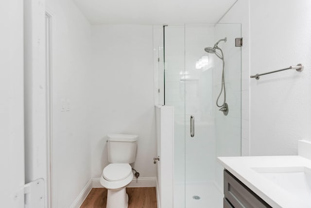 bathroom featuring wood-type flooring, vanity, toilet, and a shower with shower door