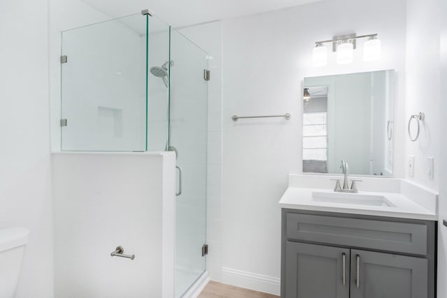 bathroom with wood-type flooring, vanity, toilet, and an enclosed shower