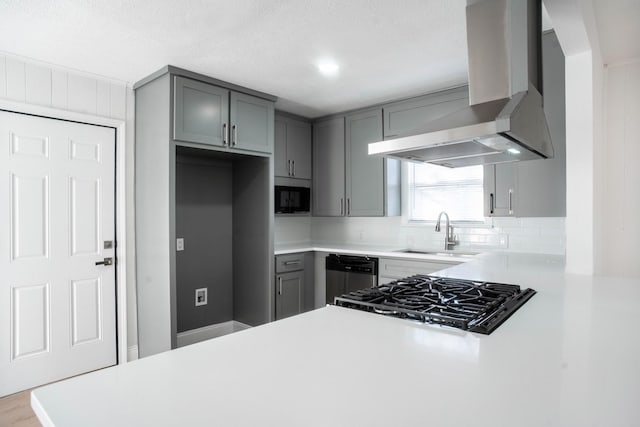 kitchen featuring stainless steel dishwasher, wall chimney exhaust hood, gray cabinetry, and sink