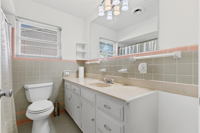 bathroom with tile patterned floors, toilet, vanity, and tile walls