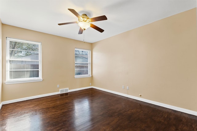 empty room featuring plenty of natural light, dark wood-type flooring, and ceiling fan