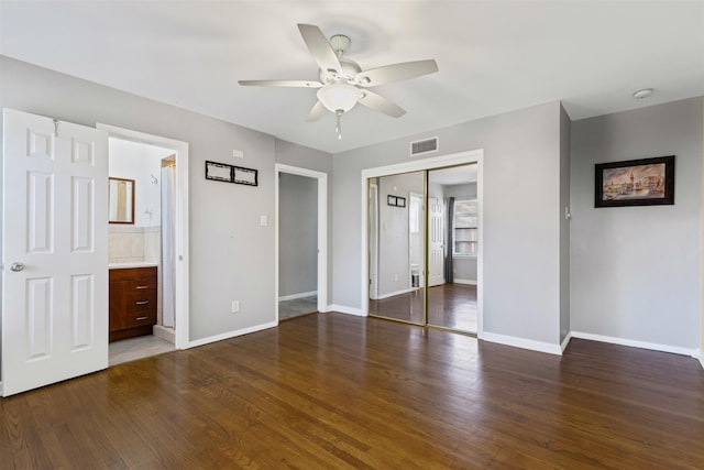 unfurnished bedroom with dark hardwood / wood-style floors, connected bathroom, ceiling fan, and a closet