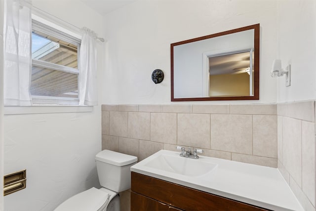 bathroom with vanity, toilet, and tile walls