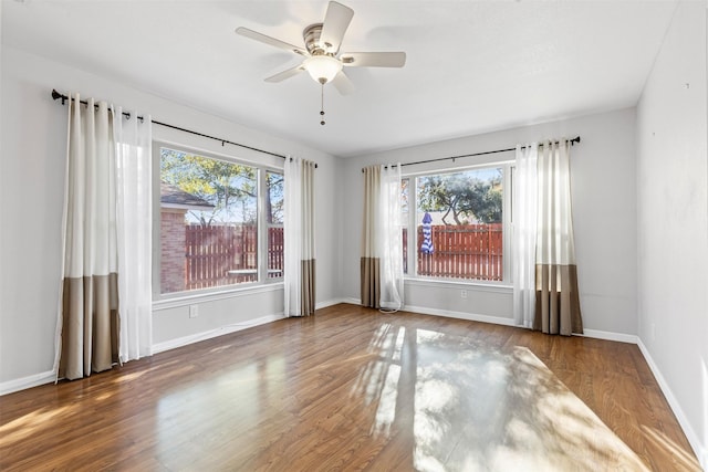 empty room featuring ceiling fan, a healthy amount of sunlight, and wood-type flooring