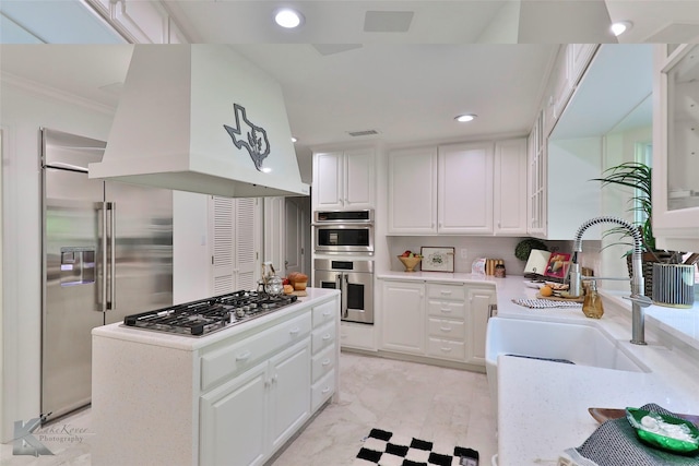 kitchen with white cabinetry, sink, stainless steel appliances, premium range hood, and crown molding