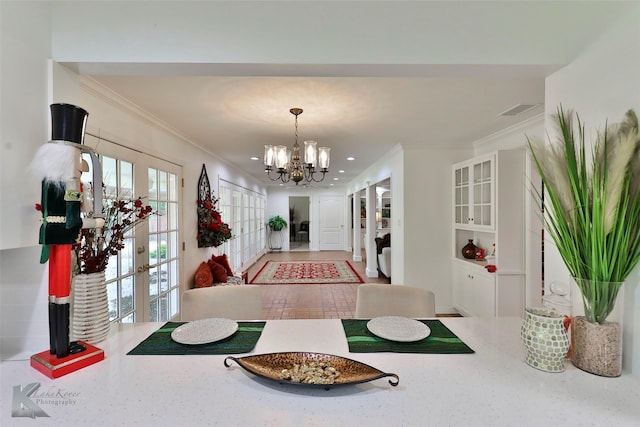 dining area with french doors, ornamental molding, and a notable chandelier