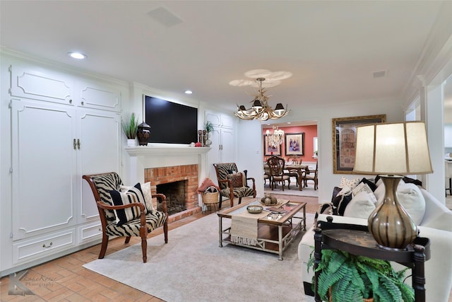 living room featuring a chandelier, ornamental molding, and a brick fireplace