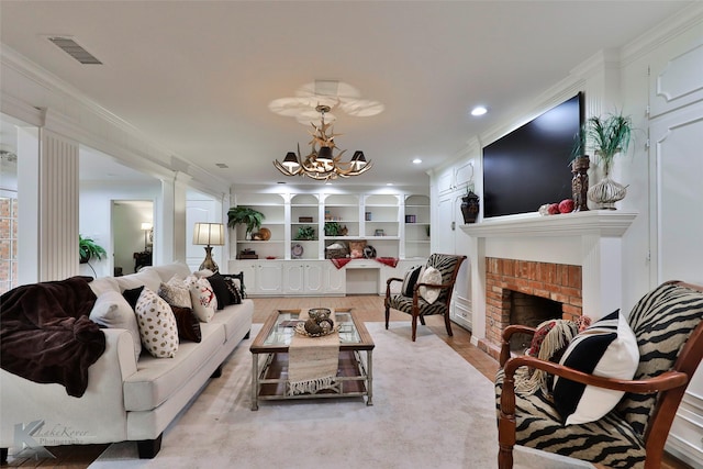 living room featuring a brick fireplace, built in shelves, crown molding, an inviting chandelier, and light hardwood / wood-style flooring