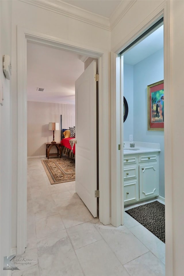 corridor featuring light tile patterned floors, crown molding, and sink