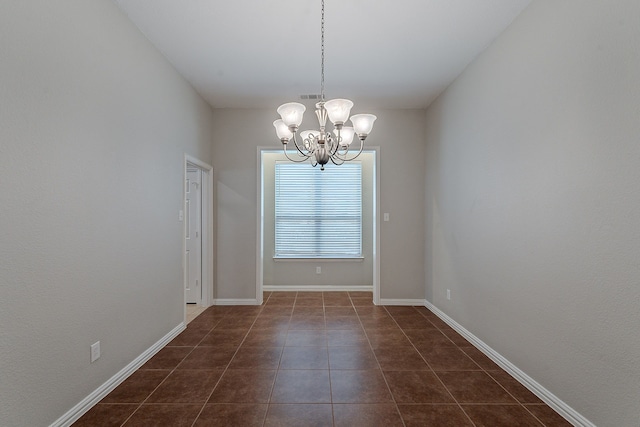 empty room featuring a chandelier and dark tile patterned flooring