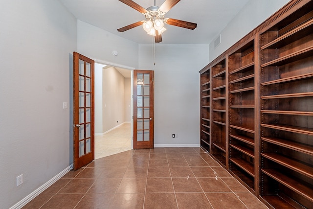 tiled spare room featuring ceiling fan and french doors