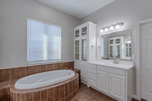 bathroom featuring tile patterned flooring, vanity, and a relaxing tiled tub