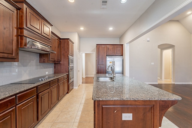 kitchen featuring sink, stainless steel fridge with ice dispenser, a kitchen island with sink, black electric stovetop, and light tile patterned floors