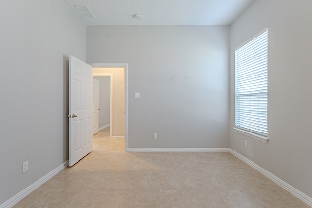 unfurnished room with light tile patterned floors and a wealth of natural light