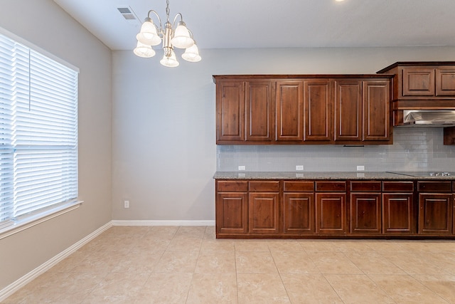 kitchen with backsplash, black electric cooktop, wall chimney range hood, an inviting chandelier, and hanging light fixtures